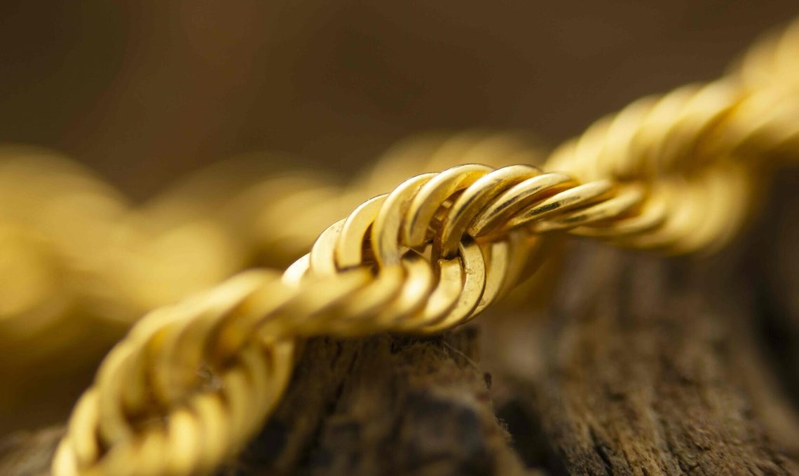 Gold rope chain necklace resting on weathered wood